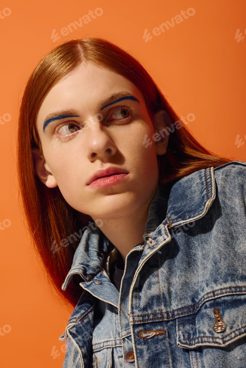 Preview: Expressive portrait of a young man with long red hair set against a vibrant orange backdrop