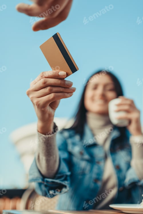 Preview: young woman paying with credit card in cafe outdoors