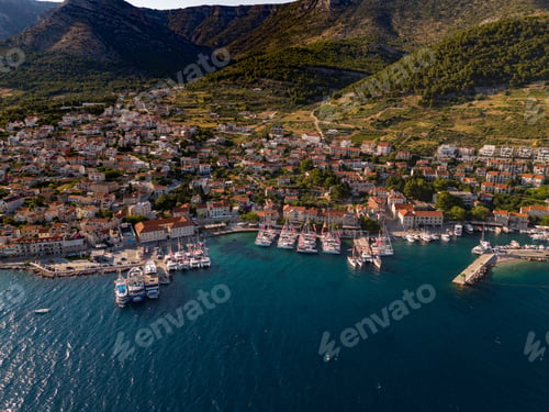 Preview: Aerial view of a coastal town with a marina, surrounded by mountains and blue waters. Bol, Croatia