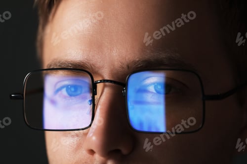 Preview: Man wearing glasses with reflection on dark background, closeup