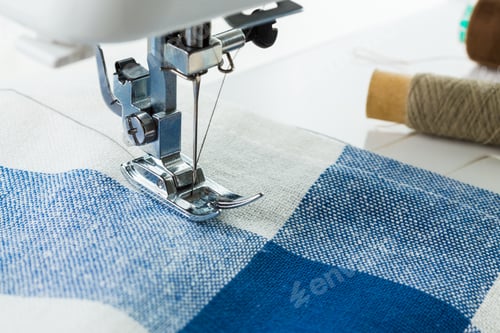 Preview: Sewing machine stitching blue and white fabric patchwork at a creative workspace