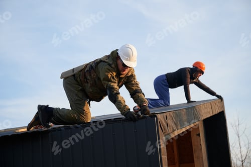 Preview: Builder installing corrugated iron sheet used as facade of future wooden frame house.