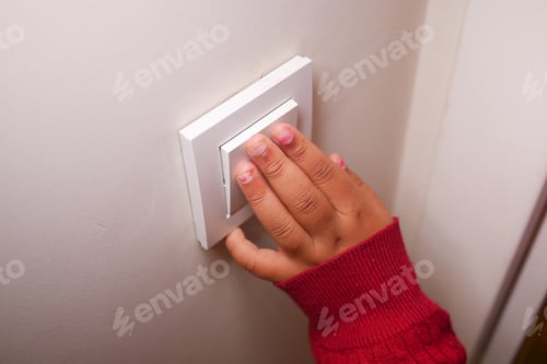 Preview: Child reaching to turn on light switch in cozy indoor setting