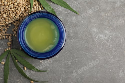 Preview: Jar of hemp cream and seeds on grey stone table, flat lay with space for text. Organic cosmetics