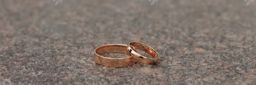 Preview: Banner two golden wedding bands on textured surface.