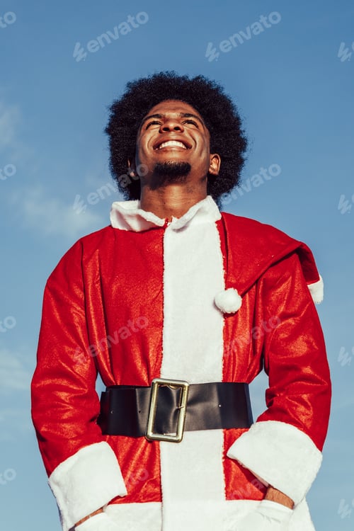 Preview: african american santa claus with afro hair looking up and smiling over sky background