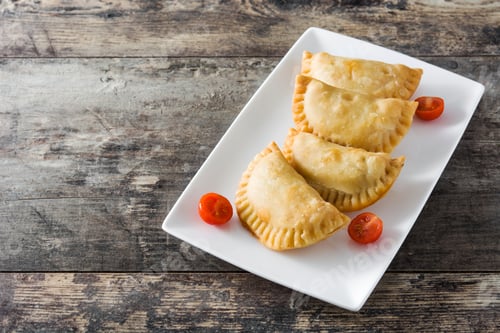 Preview: Fried empanadas with cherry tomatoes on rustic wooden table