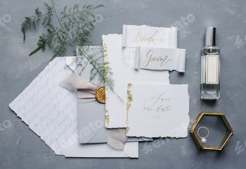 Preview: Flat lay of minimalistic wedding invitation details - letters, plant