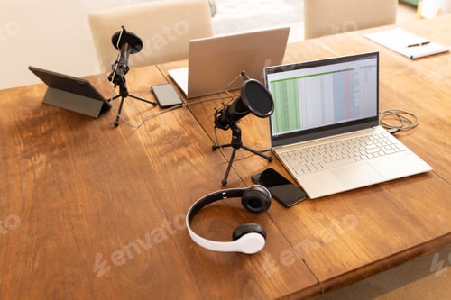 Preview: Podcasting setup with laptops, microphones, and headphones on wooden table, copy space