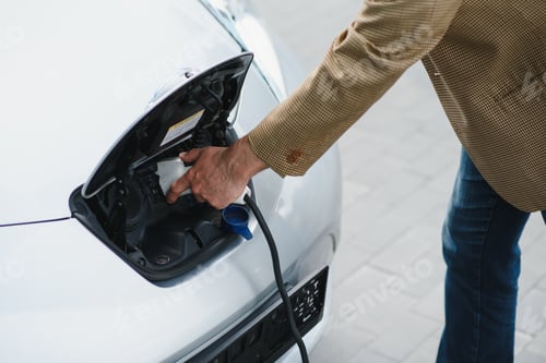 Preview: a businessman charges an electric car