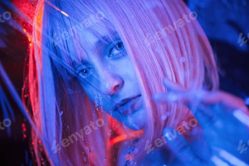 Preview: Posing for camera. Stylish woman with white hair is behind wet transparent plastic sheet
