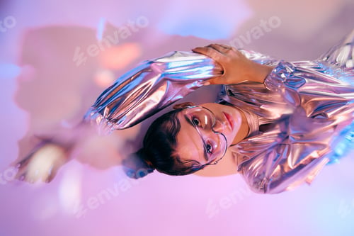 Preview: Stylish woman in holographic attire embraces vibrant colors in a futuristic setting