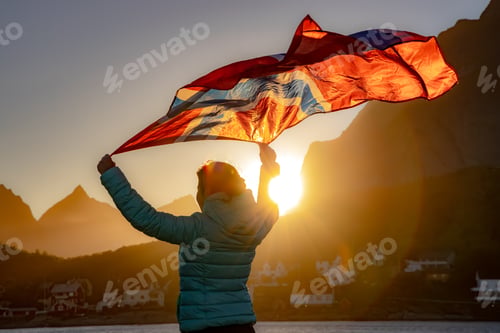 Preview: Woman waving the flag of Norway at sunset