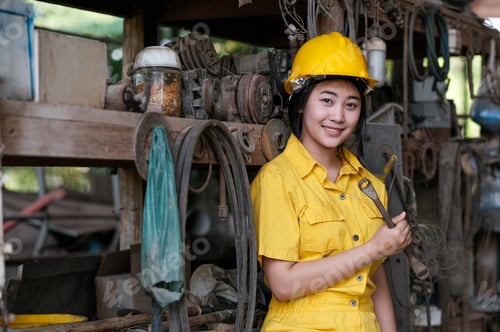 Preview: Asian pretty technician girl hold old wrench and stand in front of shelves with a lot of tools