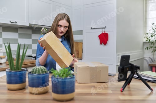 Preview: Woman recording video on smartphone unpacking cardboard box. Pet parrot helping to unpack