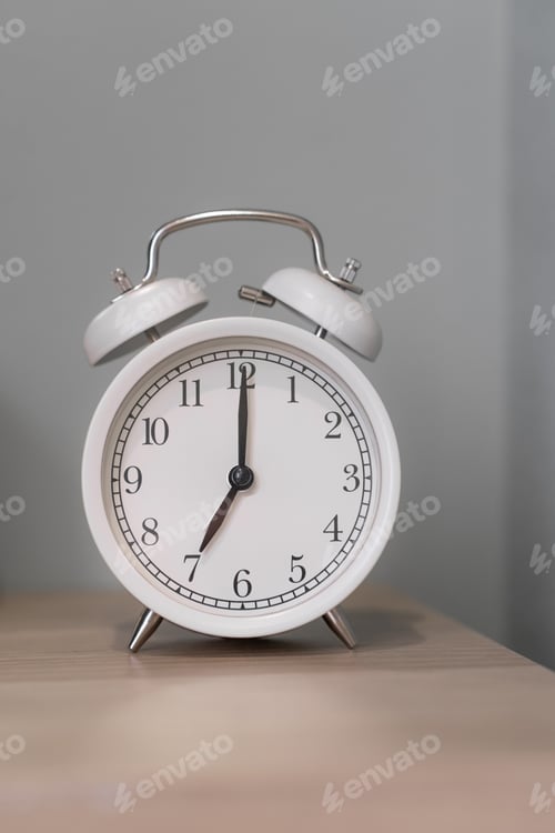 Preview: Close-up of a round white alarm clock on a table in the bedroom.