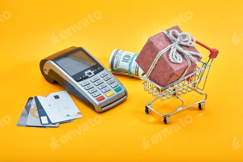 Preview: Mini shopping trolley cart full of gift box, dollar banknotes and credit cards on yellow background