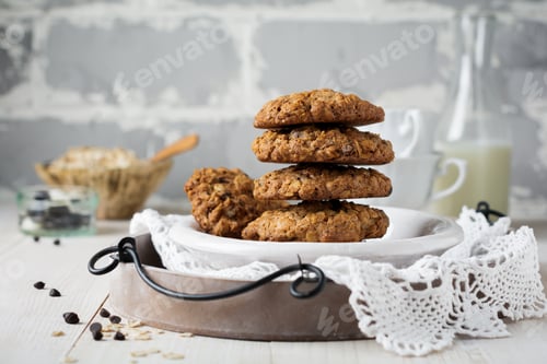 Preview: Stack of oatmeal cookies with chocolate on a light background with flakes and a bottle of milk. Sele