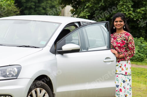 Preview: happy young Indian woman standing next to her new buying car at outdoor.