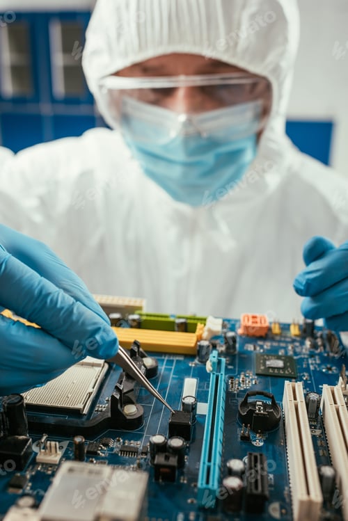 Preview: selective focus of engineer holding tweezers while testing computer motherboard