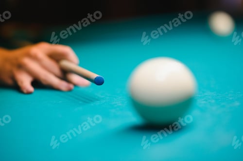 Preview: game of billiards the hand of a man with a billiard cue aims at a billiard ball