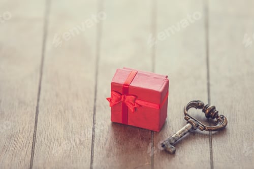 Preview: Retro key and little red gift on wooden table.