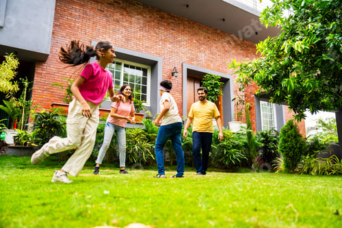 Preview: Indian family playing blindfold game in home garden, spending joyful outdoor time together