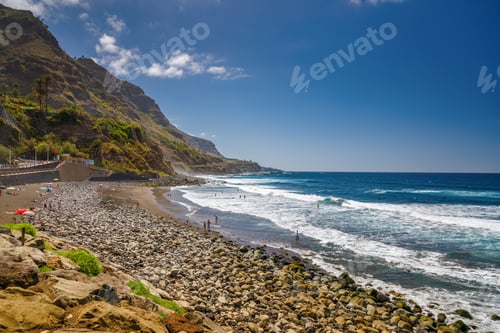 Preview: The rugged terrain of El Socorro beach, with waves crashing along the rocks and steep, green cliffs