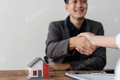 Preview: Real estate agent or realtor shakes hands with her client after making the deal in the office
