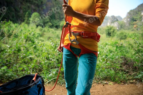 Preview: Rock climber belaying while her partner is climbing on the edge of the cliff.