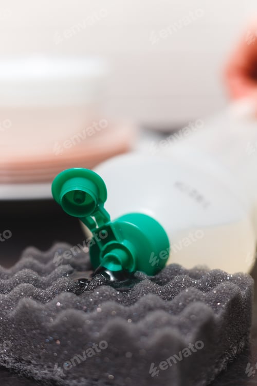 Preview: Close-up of Detergent Bottle and Sponge on Kitchen Table. The Gel Flows on a Sponge from Bottle