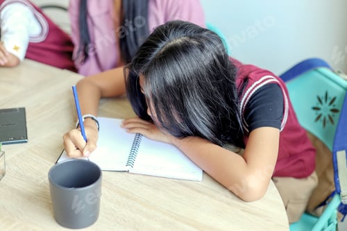 Preview: Tired Little Girl Doing Homework With Writing On Book