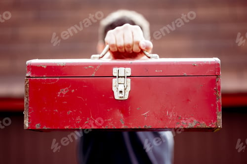 Preview: Closeup shot of a male holding a toolbox in front of his fa