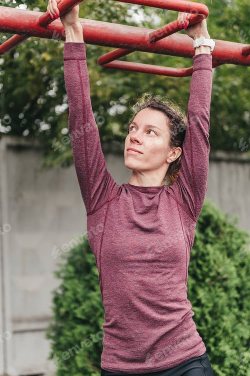 Preview: Sportswoman climbs on monkey bars on open sports ground