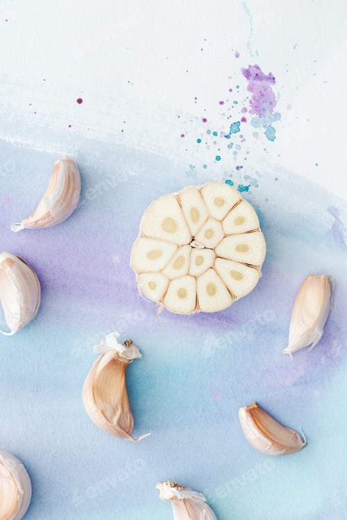 Preview: top view of sliced garlic on white surface with purple watercolor strokes