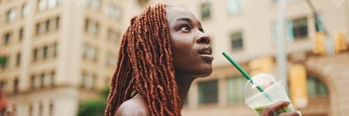 Preview: Panorama of beautiful woman walks down the street with cold drink in her hands