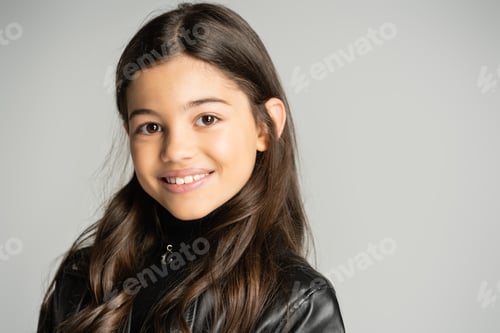 Preview: Portrait of brunette kid in leather jacket looking at camera isolated on grey