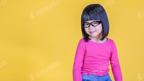 Preview: Portrait of young happy little asian nerd girl wearing glasses isolated on yellow