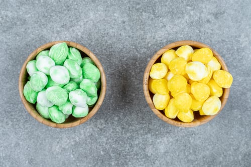 Preview: Wooden bowls of colorful candies on marble surface