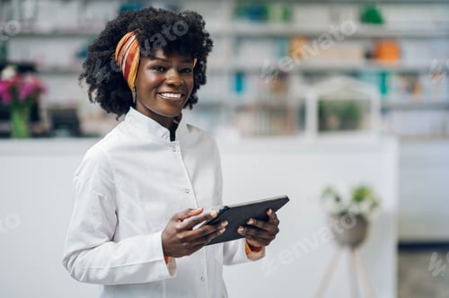 Preview: Portrait of a happy young pharmacist using a tablet in a pharmacy.