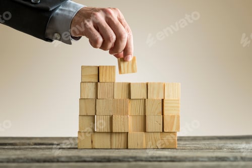 Preview: Businessman building a structure with wooden cubes on table surf