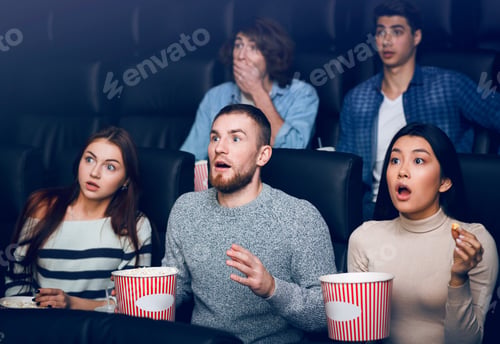 Preview: Scared young people watching new motion picture in movie theater