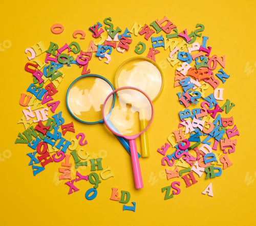 Preview: Plastic magnifying glass and wooden letters of the English alphabet on a yellow background