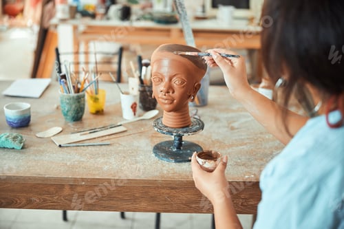Preview: Female ceramic artist painting on clay sculpture in workshop