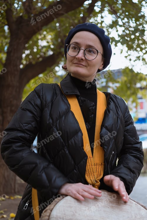 Preview: European woman playing an African drum djembe outdoors in autumn
