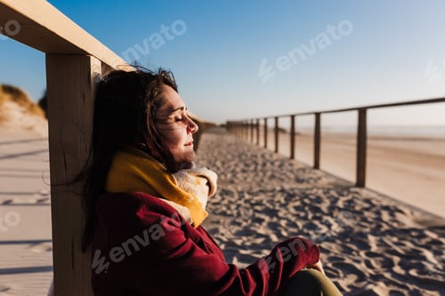 Preview: young caucasian woman with eyes closed relaxing at the beach at sunset.Holidays and relax