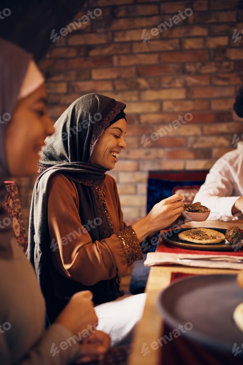 Preview: Cheerful Muslim woman enjoying in lunch with her family at home.