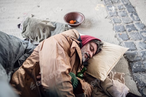 Preview: Homeless beggar man lying on the ground outdoors in city, sleeping.