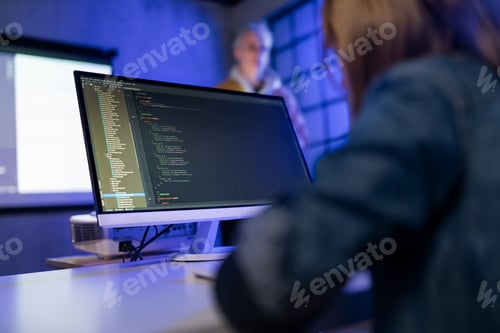 Preview: Rear view of schoolgirl using computer in classroom at school