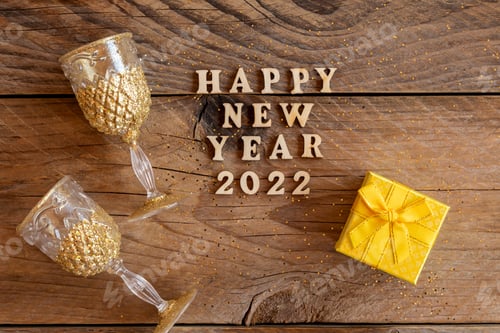 Visualização: Feliz celebração do ano novo de 2022. Taças de champanhe e caixa de presente em fundo de madeira. Lay plano